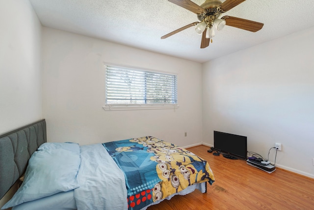 bedroom with ceiling fan, wood-type flooring, and a textured ceiling