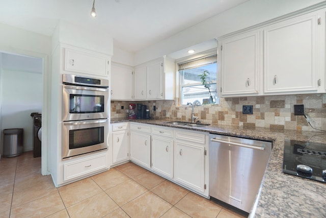 kitchen featuring backsplash, white cabinets, sink, dark stone countertops, and appliances with stainless steel finishes