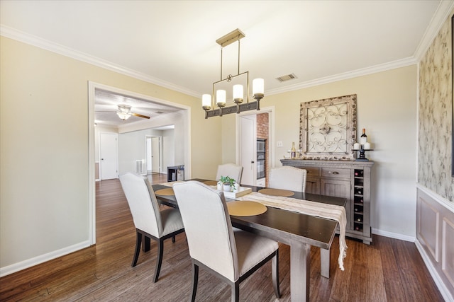 dining room featuring dark hardwood / wood-style floors, crown molding, and ceiling fan with notable chandelier