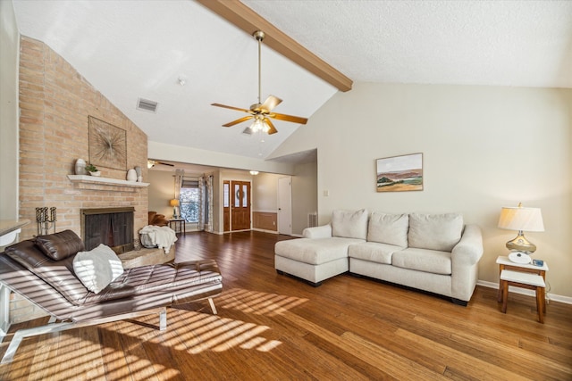 living room with hardwood / wood-style flooring, ceiling fan, a fireplace, and beamed ceiling