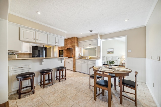 kitchen featuring white cabinets, a textured ceiling, black fridge with ice dispenser, kitchen peninsula, and a breakfast bar area