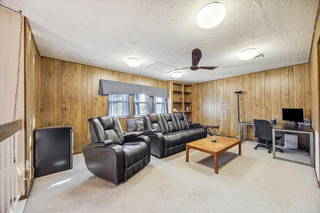 living room with wooden walls, ceiling fan, light carpet, and a textured ceiling