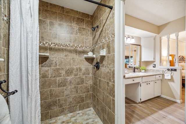 bathroom featuring hardwood / wood-style floors, vanity, walk in shower, and a textured ceiling