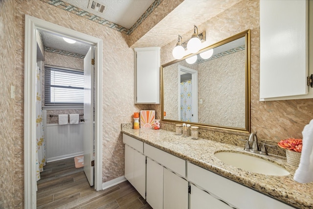 bathroom featuring a chandelier, wood-type flooring, vanity, and a textured ceiling