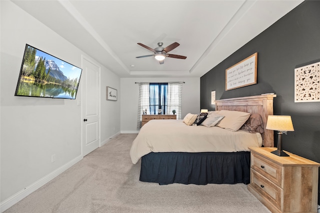 carpeted bedroom featuring ceiling fan and a tray ceiling