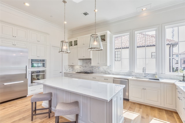 kitchen featuring appliances with stainless steel finishes, a kitchen island, sink, light hardwood / wood-style flooring, and white cabinetry