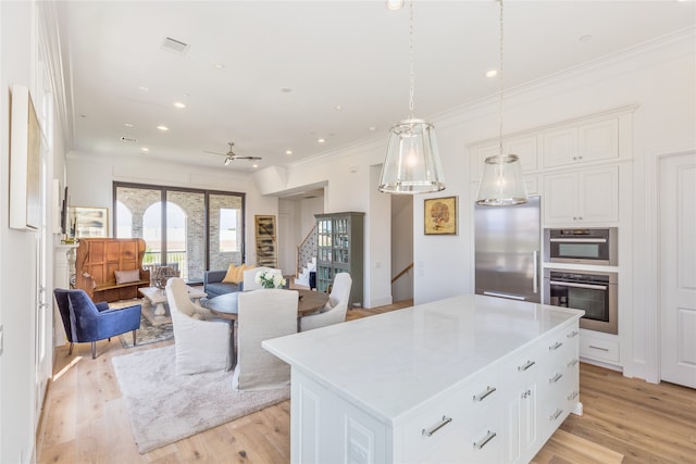 kitchen featuring light wood-type flooring, stainless steel appliances, a kitchen island, and white cabinetry