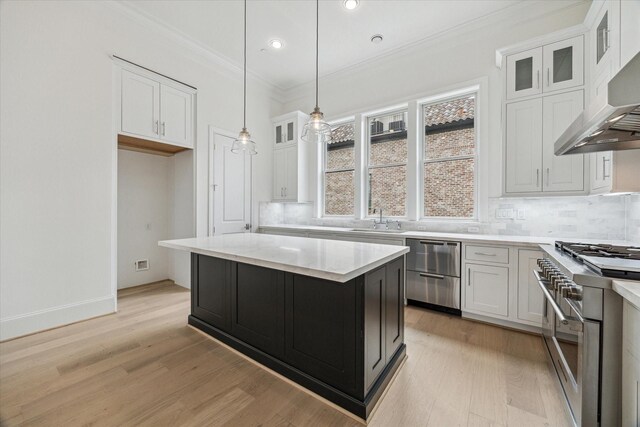 7523 Cuadro Ln, Houston, TX 77055 - kitchen with stainless steel appliances, wall chimney range hood, a sink, crown molding, and white cabinets
