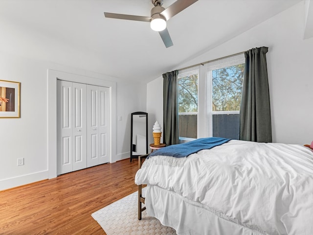 bedroom with ceiling fan, a closet, wood-type flooring, and vaulted ceiling