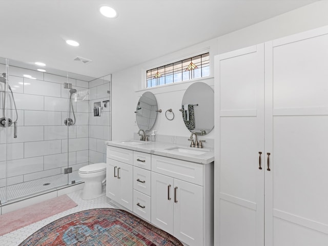 bathroom featuring tile patterned flooring, vanity, toilet, and a shower with door