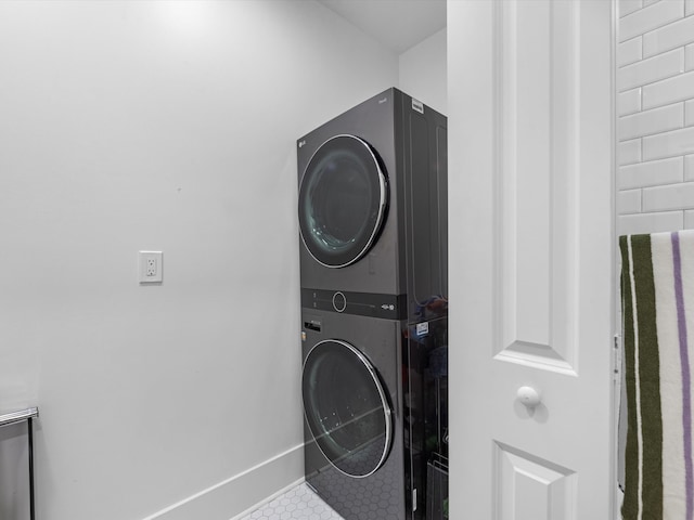 laundry room featuring tile patterned floors and stacked washer and dryer