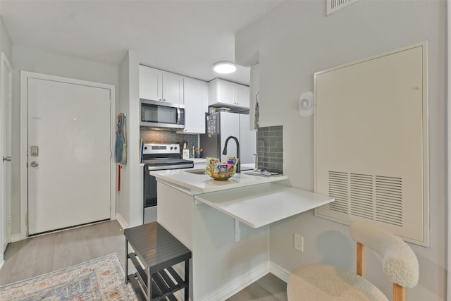 kitchen with white cabinetry, electric range oven, backsplash, kitchen peninsula, and a breakfast bar