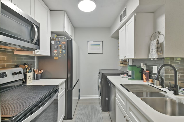 kitchen featuring white cabinets, washer and clothes dryer, stainless steel appliances, and tasteful backsplash