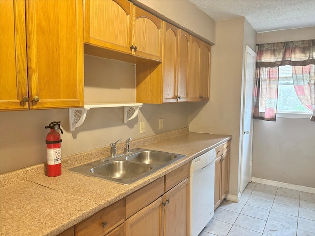 kitchen featuring dishwasher, sink, a textured ceiling, and light tile patterned floors