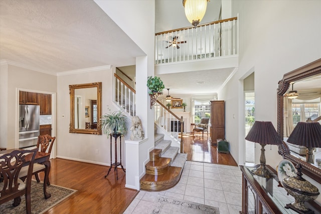 entryway with ceiling fan, light hardwood / wood-style floors, a textured ceiling, and ornamental molding