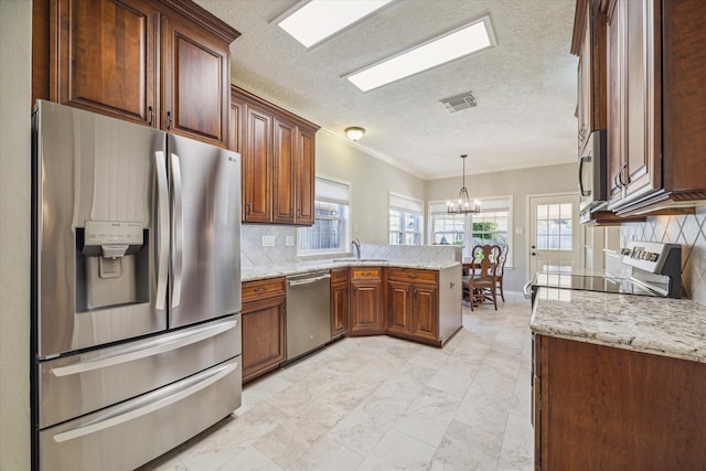 kitchen with sink, stainless steel appliances, kitchen peninsula, a chandelier, and decorative backsplash