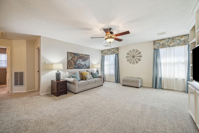 living room featuring a textured ceiling, carpet floors, plenty of natural light, and ceiling fan