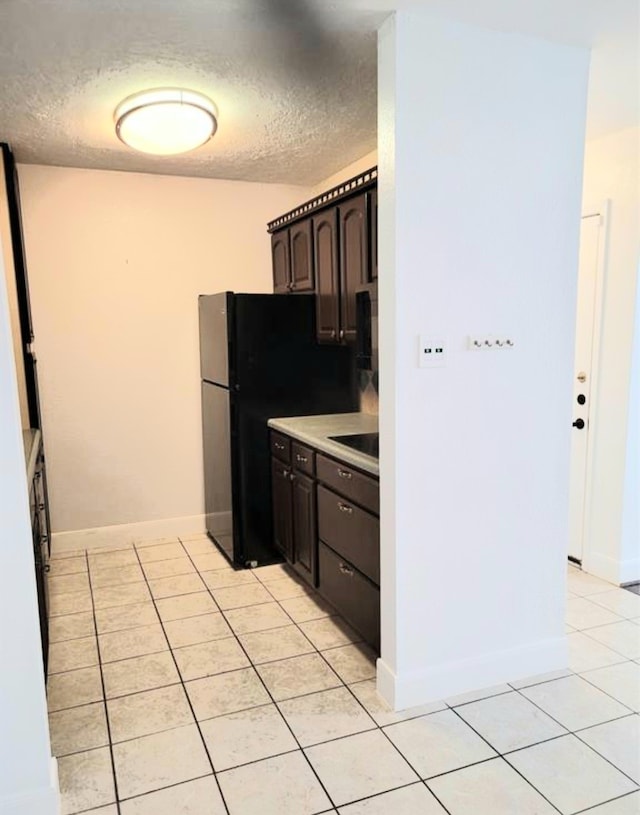 kitchen featuring dark brown cabinetry, a textured ceiling, and light tile patterned floors