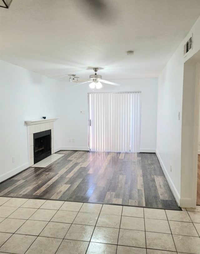 unfurnished living room with light hardwood / wood-style floors, ceiling fan, and a tiled fireplace