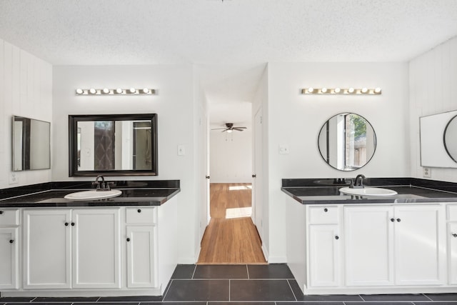 bathroom featuring hardwood / wood-style floors, vanity, wood walls, ceiling fan, and a textured ceiling