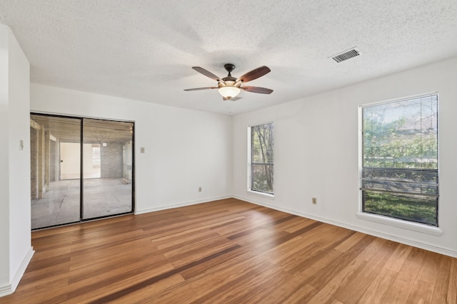 unfurnished room with hardwood / wood-style flooring, ceiling fan, and a textured ceiling