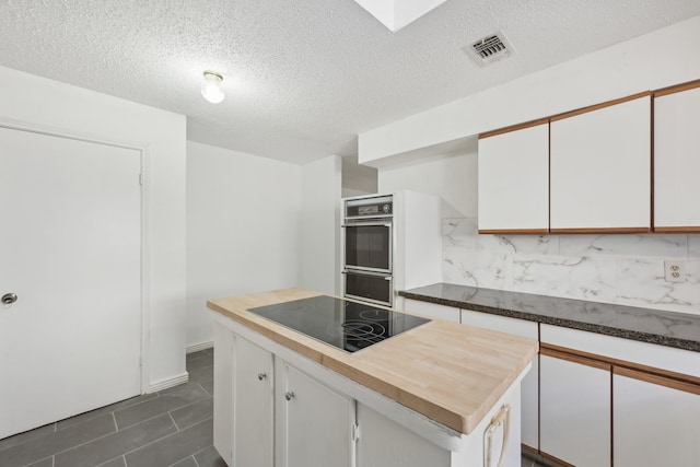 kitchen featuring white cabinets, black appliances, a textured ceiling, and a kitchen island