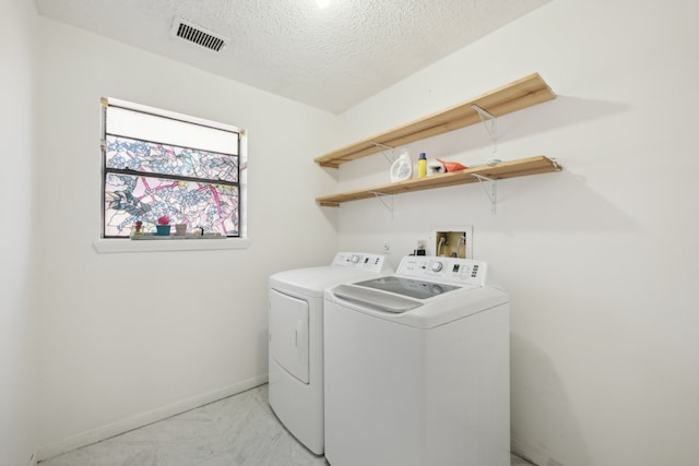 laundry area featuring a textured ceiling and washing machine and dryer