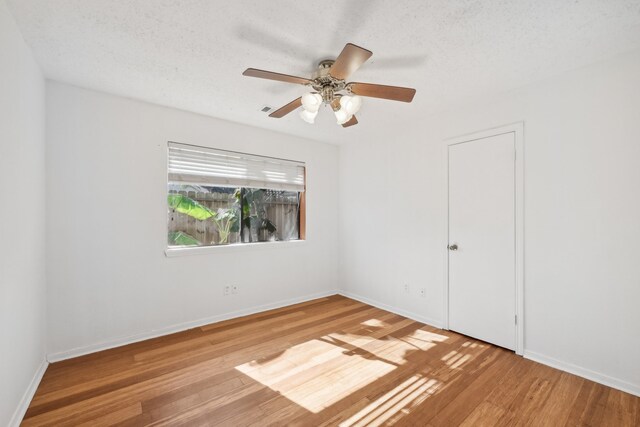 empty room featuring a textured ceiling, hardwood / wood-style flooring, and ceiling fan