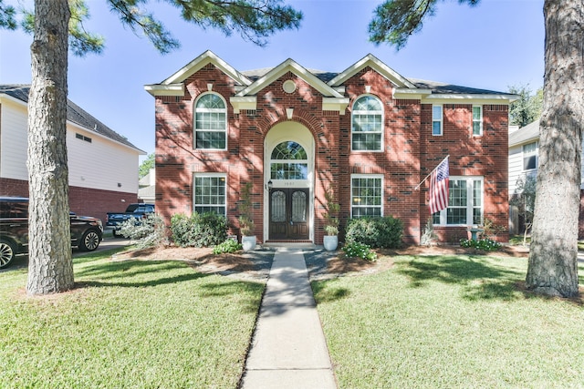 colonial home featuring french doors and a front lawn