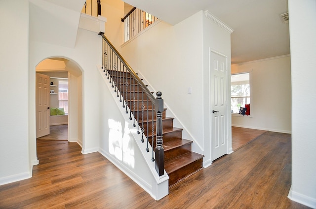 stairs with crown molding and wood-type flooring