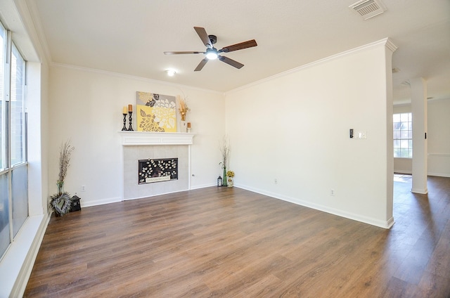 unfurnished living room featuring ceiling fan, ornamental molding, a tiled fireplace, and hardwood / wood-style floors