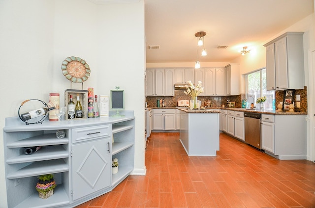 kitchen with tasteful backsplash, dishwasher, a kitchen island, and sink