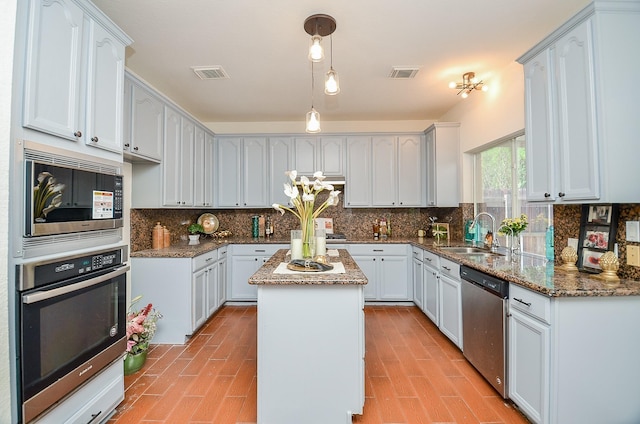 kitchen with sink, dark stone countertops, hanging light fixtures, a center island, and stainless steel appliances