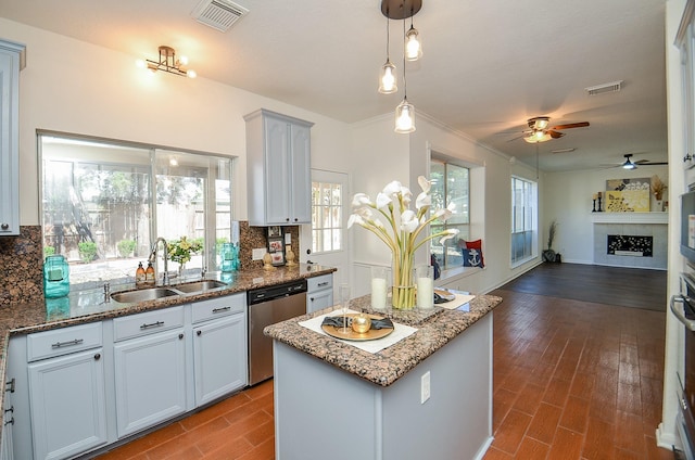 kitchen featuring sink, backsplash, white cabinets, a kitchen island, and stainless steel dishwasher