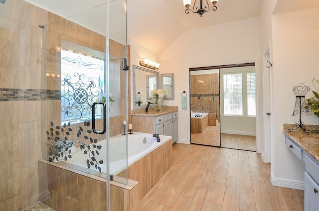 bathroom featuring an inviting chandelier, lofted ceiling, vanity, and plus walk in shower