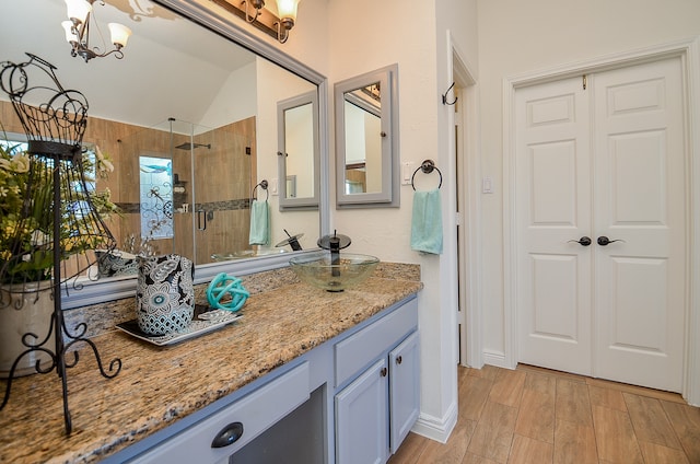 bathroom with vanity, vaulted ceiling, tiled shower, and a chandelier