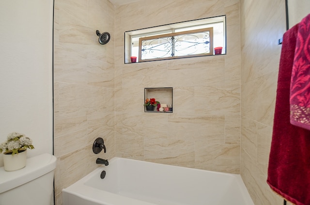 bathroom featuring tiled shower / bath combo and toilet