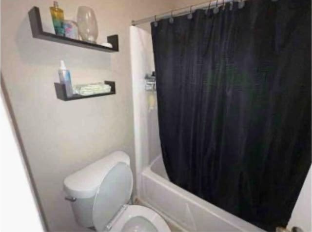 bathroom featuring shower / bath combo with shower curtain and toilet