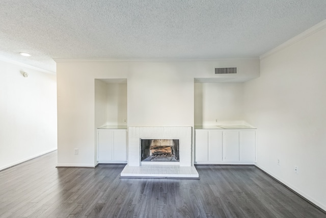 unfurnished living room with a fireplace, dark hardwood / wood-style flooring, a textured ceiling, and ornamental molding