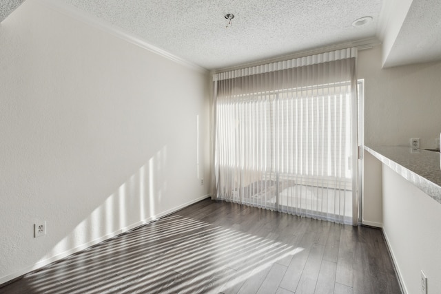 empty room with a textured ceiling, dark hardwood / wood-style flooring, and crown molding