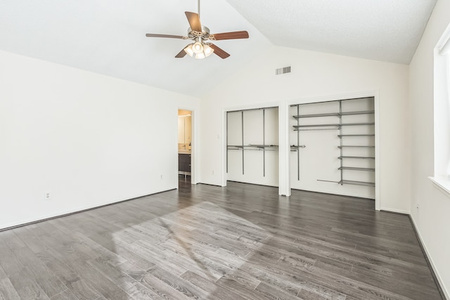 unfurnished bedroom featuring lofted ceiling, two closets, ensuite bathroom, ceiling fan, and dark hardwood / wood-style floors