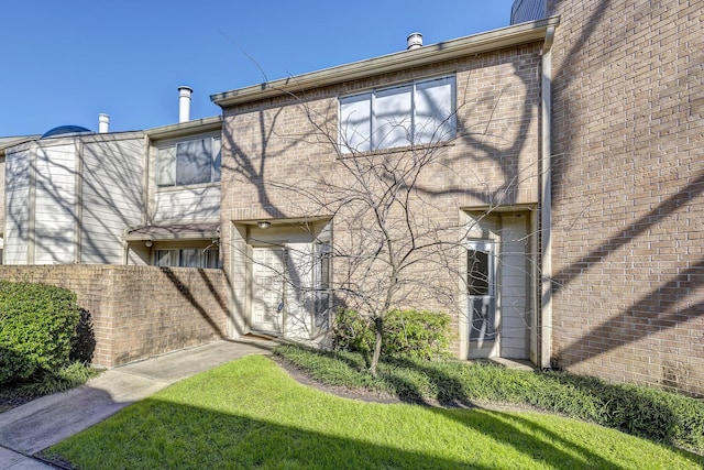 exterior space featuring a yard, fence, and brick siding