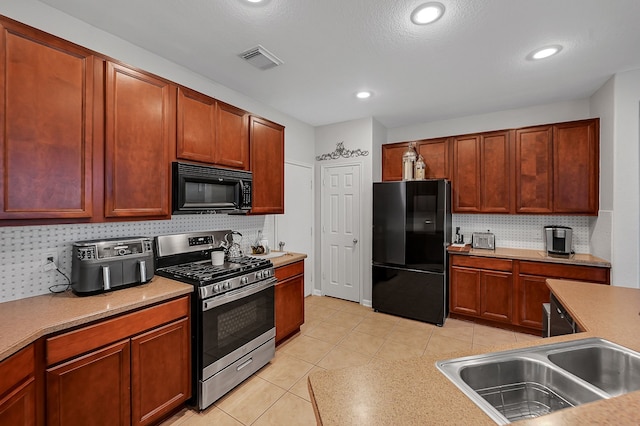 kitchen featuring backsplash, sink, light tile patterned floors, and black appliances