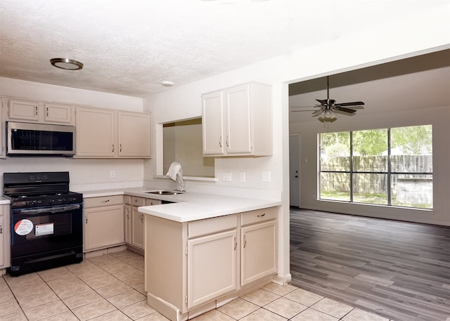 kitchen with ceiling fan, sink, black range with gas stovetop, light hardwood / wood-style flooring, and kitchen peninsula