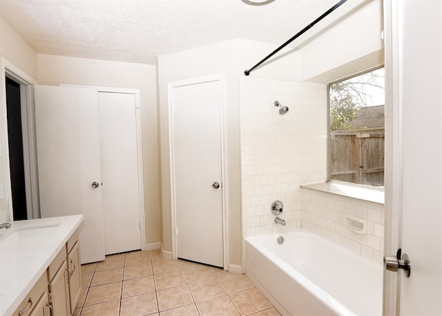 bathroom featuring vanity, a textured ceiling, tiled shower / bath combo, and tile patterned floors