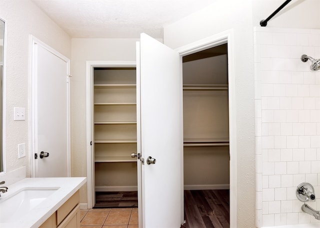 bathroom featuring a textured ceiling, vanity, hardwood / wood-style flooring, and shower / washtub combination