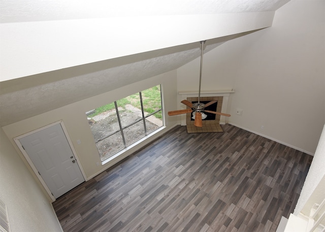 unfurnished living room with a textured ceiling, ceiling fan, dark hardwood / wood-style floors, and lofted ceiling