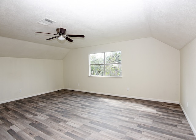 additional living space featuring lofted ceiling, ceiling fan, wood-type flooring, and a textured ceiling