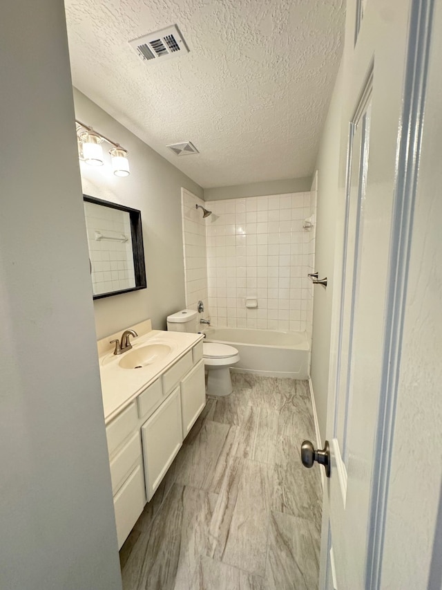 full bathroom with vanity, a textured ceiling, toilet, and tiled shower / bath combo