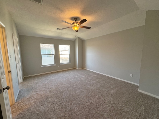 spare room with carpet, ceiling fan, lofted ceiling, and a textured ceiling